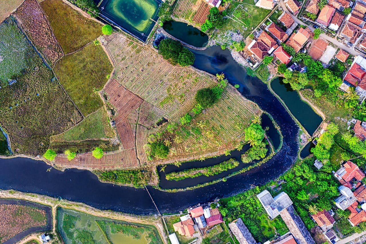 Stunning aerial photograph of lush farmland and a winding river in Banten, Indonesia.